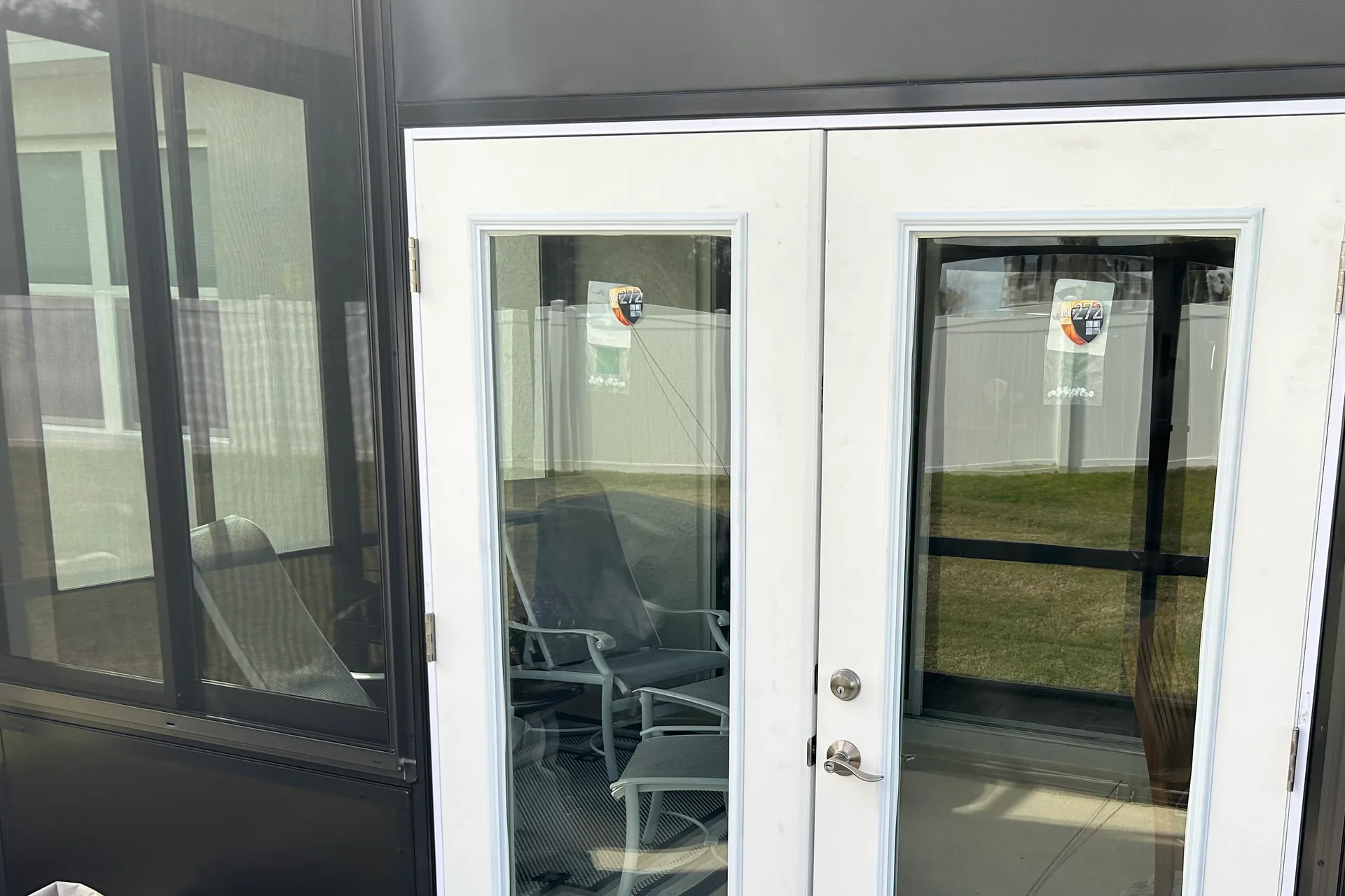 White full-lite French doors installed in the dark framing of a screened Central Florida lanai