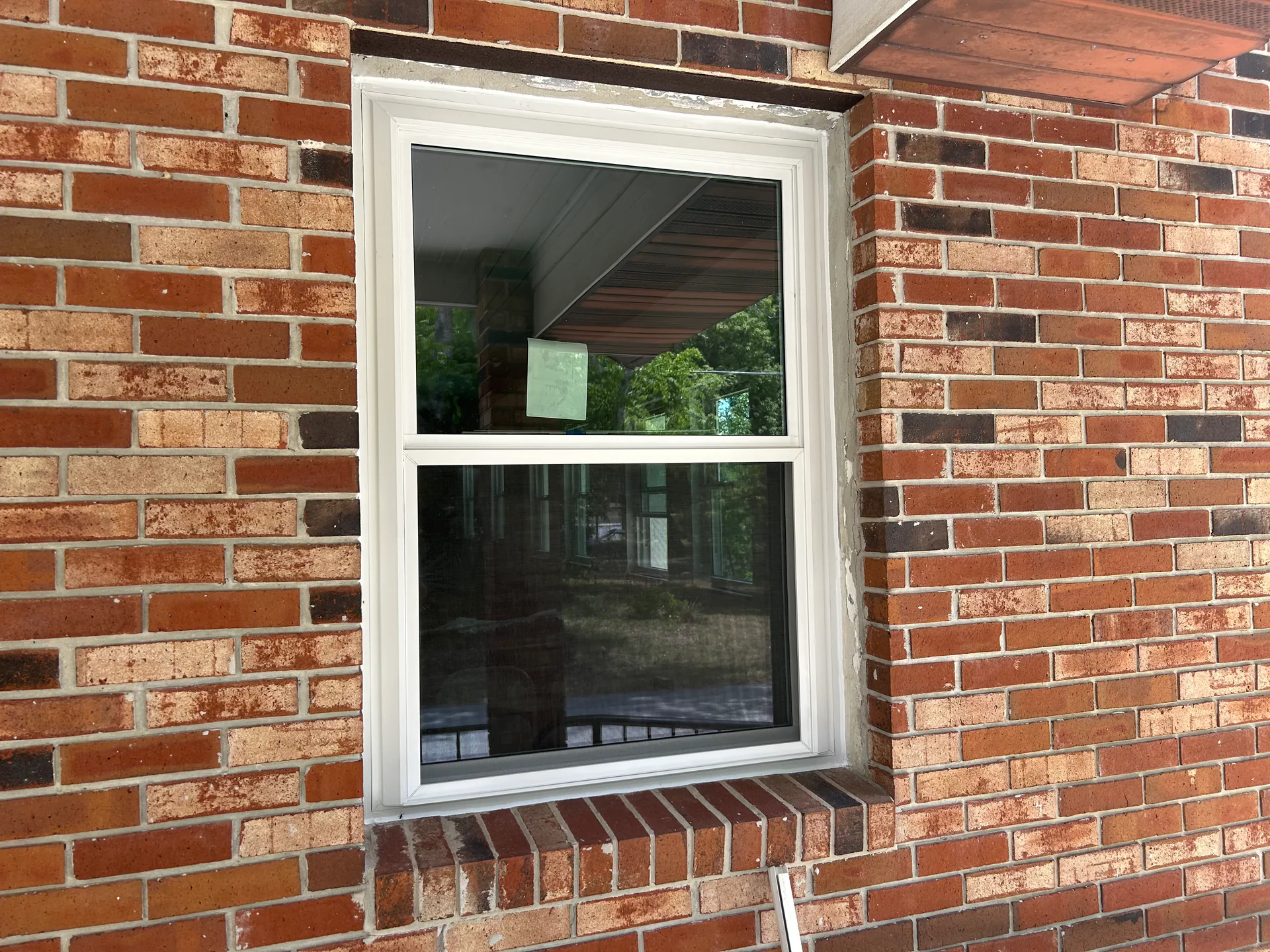 A white single-hung replacement window installed in a red brick Central Florida home